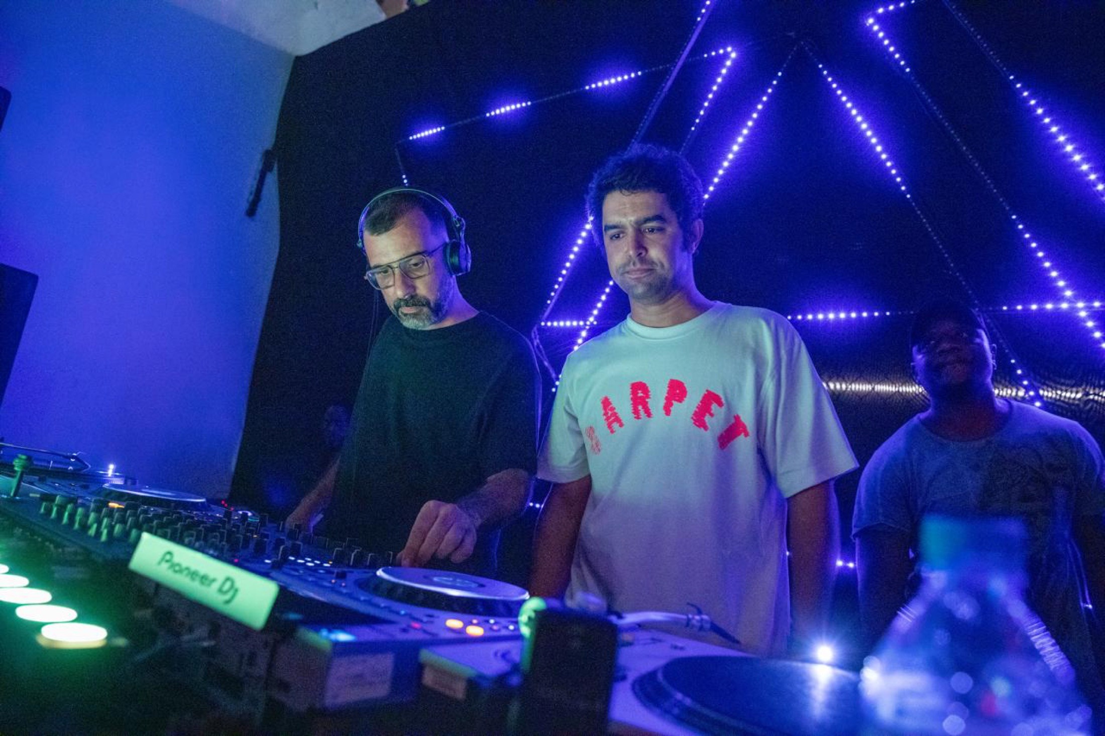 KULAS na cabine sob luz azul e magenta.