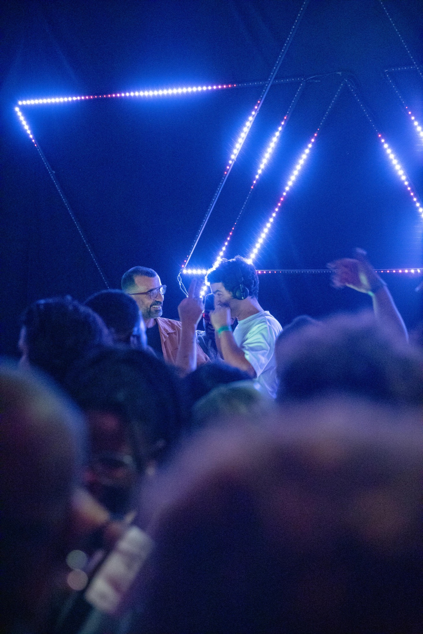 KULAS visto através do público sob luzes azuis geométricas.